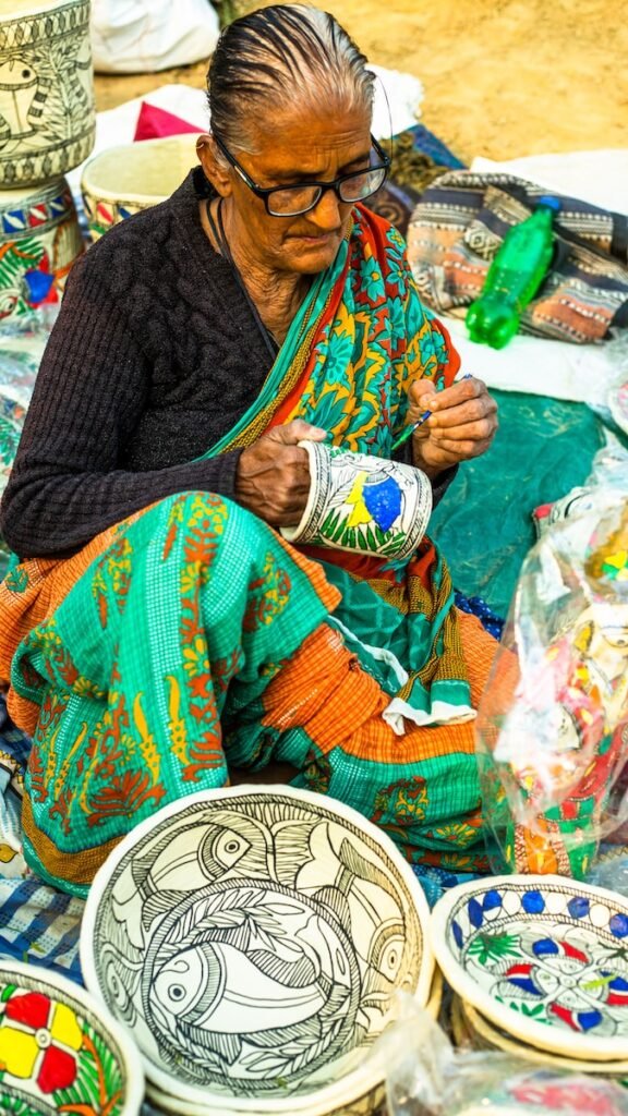 a woman sitting on the ground working on a piece of art